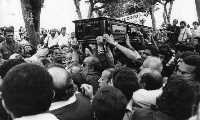 Caixão com o corpo de Mariel é erguido sobre multidão no cemitério do Caju, em 1981