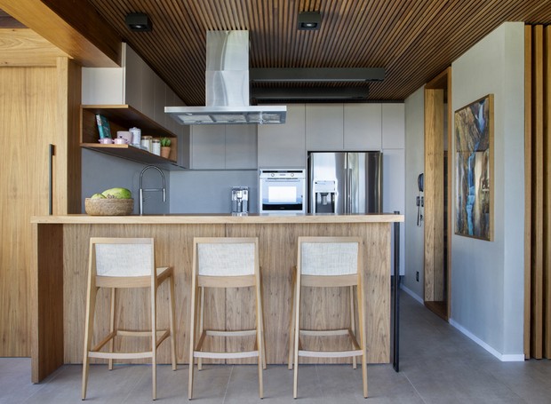 A bancada da cozinha é feita de eucalipto lima. Está área fica conectada ao living, promovendo integração e contemplando a vista da praia da varanda (Foto: Divulgação)