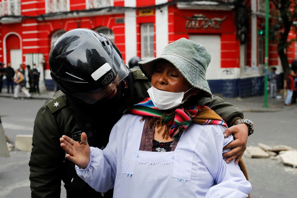 Policial retira mulher de região de confronto entre forças de segurança e manifestantes em La Paz, na Bolívia, nesta quarta-feira (13) — Foto: Marco Bello/Reuters