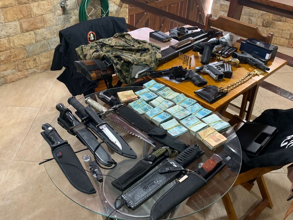 Dinheiro e armas apreendidas na casa de um agente penitenciário — Foto: Reprodução/TV Globo