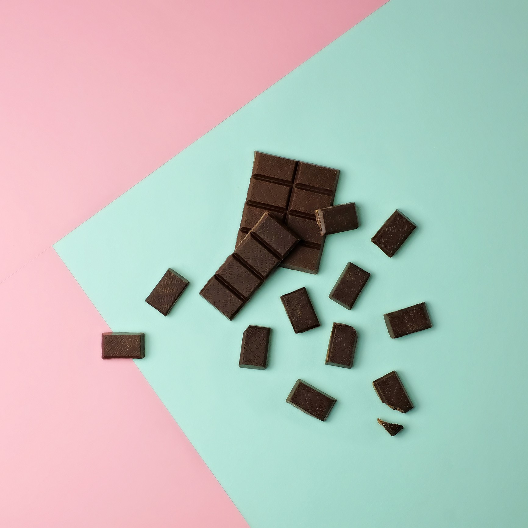 Dark chocolate bar pieces on a pink and mint green color blocked background. (Foto: Getty Images)