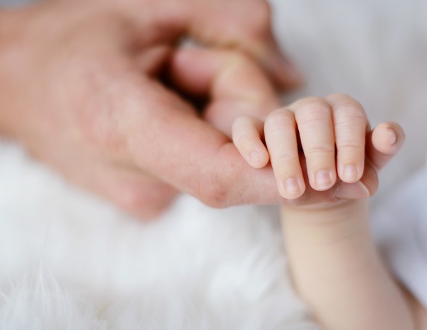 Pai segurando a mão de bebê recém-nascido (Foto: Pexels)