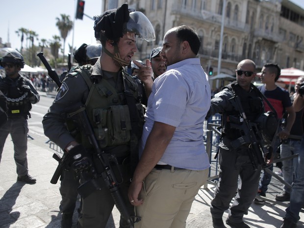 Policial israelense discute com palestino que protestava contra marcha  (Foto: Ahmad Gharabli/AFP)