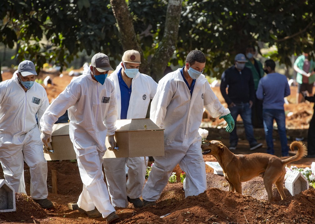 20 de maio de 2020 - Funcionários do cemitério da Vila Formosa, em São Paulo, enterram vítima do novo coronavírus (COVID-19) — Foto: Andre Penner/AP