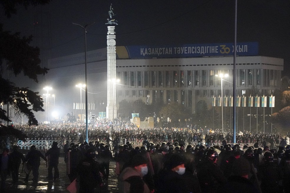 Forças de segurança observam manifestantes no centro de Almaty, a maior cidade do Cazaquistão, durante protesto em 5 de janeiro de 2022 — Foto: Vladimir Tretyakov/AP