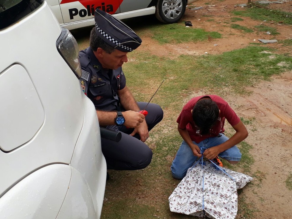 Sem saber o que era, Adrian abre o presente que ganhou dos PMs (Foto: Bárbara Leão/Jornal da Região)
