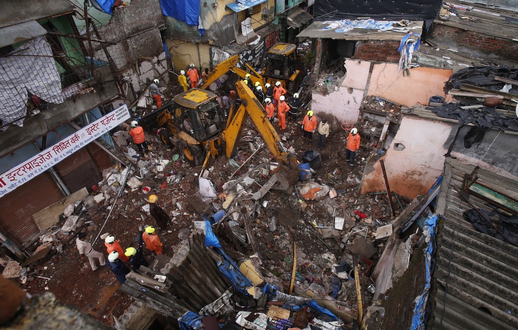Equipes de resgate limpam os escombros em busca de desaparecidos após prédio de 3 andares desabar em meio às fortes chuvas de monções em Mumbai, na Índia, em 10 de junho de 2021 — Foto: Rafiq Maqbool/AP