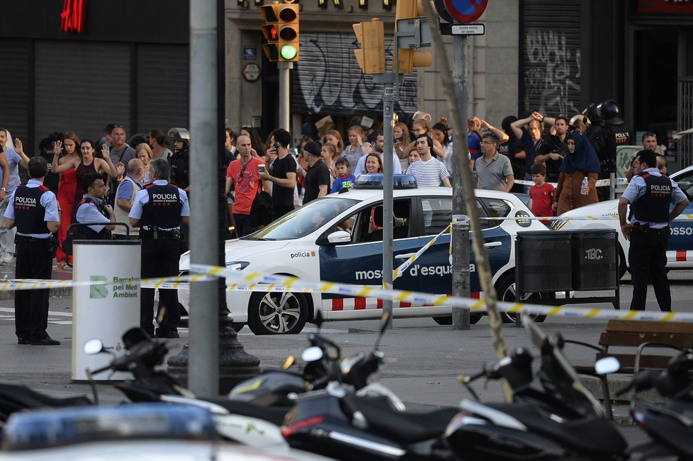Pessoas deixam restaurante com as mãos para o alto cercadas por policiais depois do atentado na Barcelona (Foto: Josep LAGO / AFP)