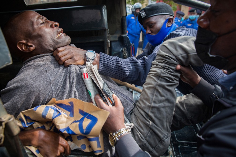 Manifestante é preso e colocado na parte de trás de um veículo por policiais enquanto pessoas exigem que o governo queniano tome medidas para melhorar as condições de vida durante a pandemia de Covid-19, durante marcha de 1º de maio que marca o Dia Internacional do Trabalho, em Nairóbi — Foto: Ed Ram/AFP