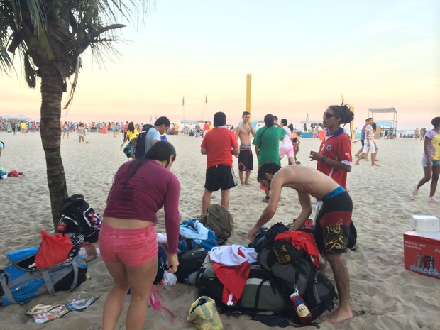 Grupo arruma pertences após tomarem banho na praia (Foto: Matheus Rodrigues/ G1)