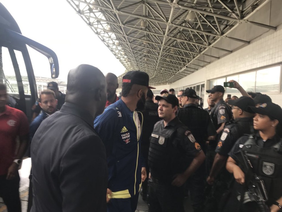 ... ao ouvir os xingamento, o goleiro para e encara o grupo, sendo protegido por policiais no Galeão (Foto: Amanda Kestelman)