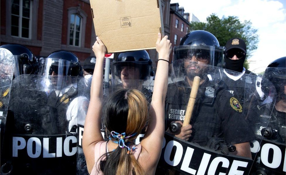 Mulher protesta enquanto policiais bloqueiam a praça Lafayette, no centro de Washington  (Foto: Getty Images via BBC)