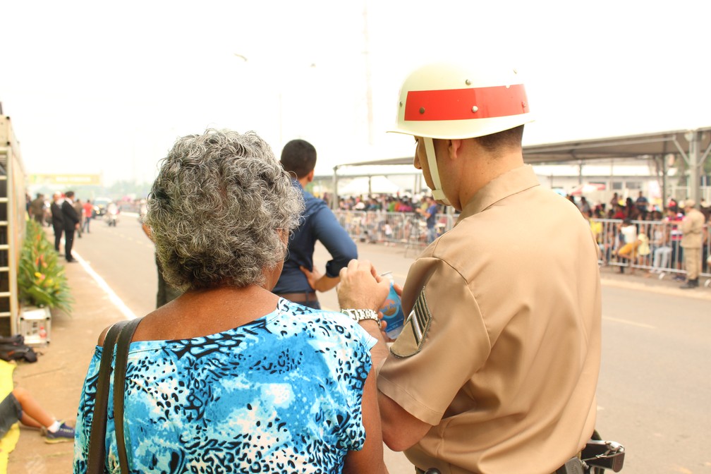 Segurança ajuda idosa durante desfile militar em Porto Velho. (Foto: Pedro Bentes/G1)
