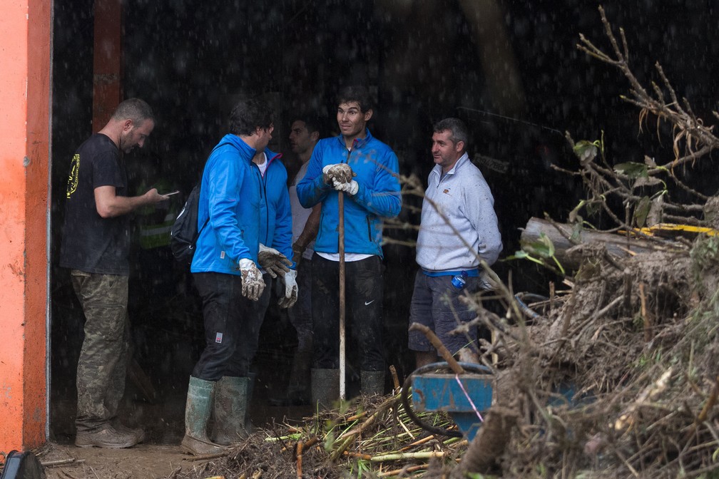 O tenista espanhol Rafael Nadal trabalha com moradores para limpar a lama de suas casas após inundações em Sant Llorenc, a 60 quilômetros a leste da capital de Maiorca, Palma, nesta quarta-feira (10) — Foto: Associated Press/Francisco Ubilla