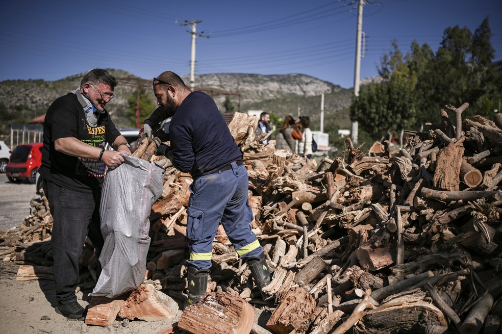 Populares gregos colocam lenha distribuída gratuitamente pela prefeitura dentro de saco — Foto: ARIS MESSINIS/AFP