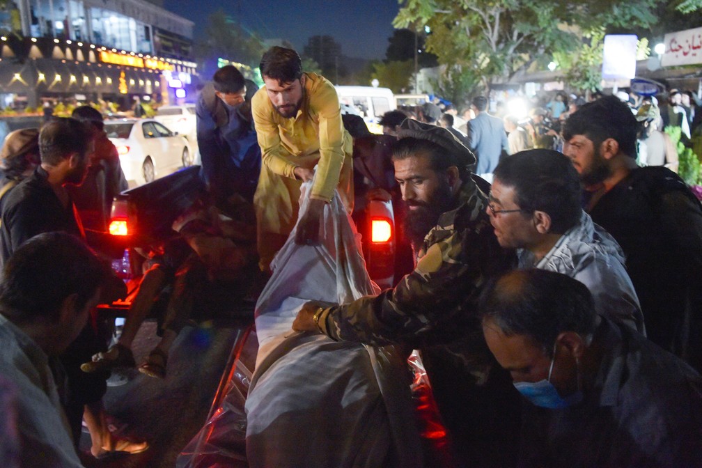 Voluntários e equipes médicas retiram corpos de uma caminhonete em frente a um hospital após o atentado terrorista no aeroporto internacional de Cabul, no Afeganistão, na quinta (26) — Foto: Wakil Kohsar/AFP