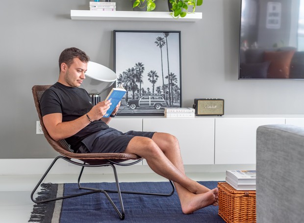 Morador | O engenheiro Andrew Morais, 28, lê um livro em sua sala de estar (Foto: Bethania Canavesi Photography / Divulgação)