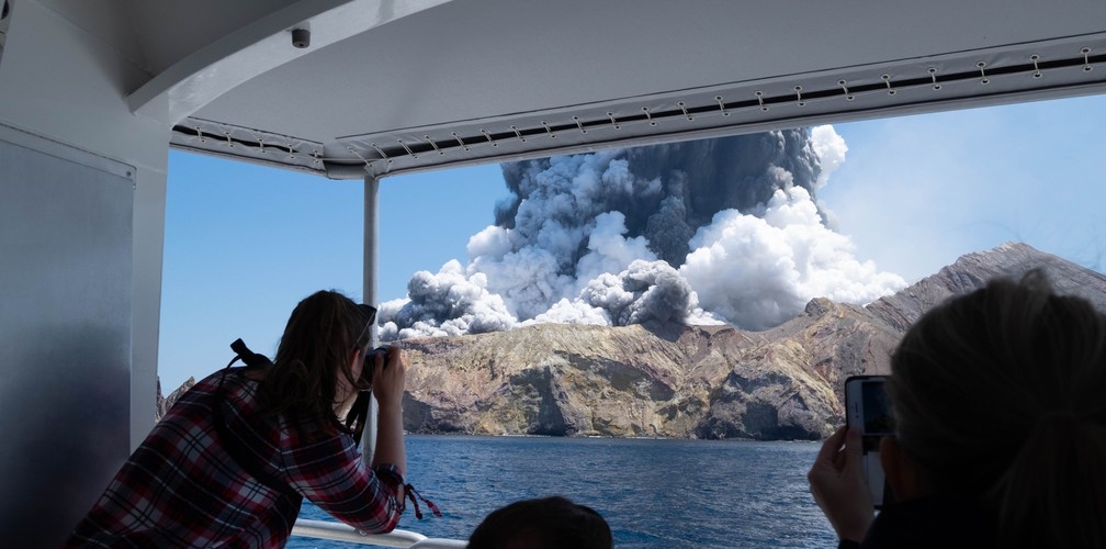Turistas fotografam o vulcão da Ilha Branca, na Nova Zelândia, logo após o início da erupção  — Foto: Michael Schade