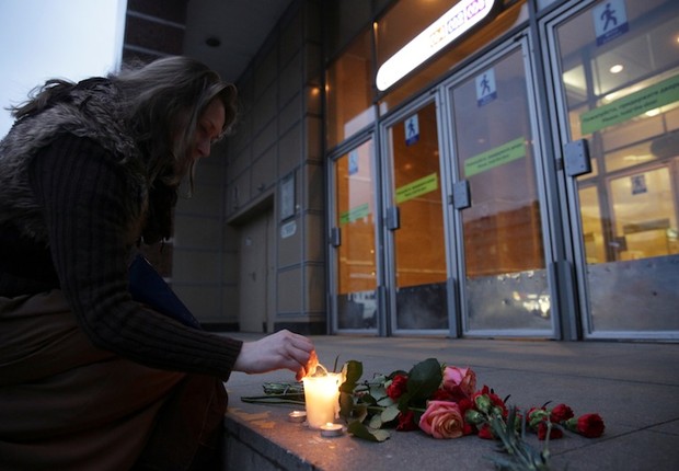 Mulher acende velas para vítimas da explosão que deixou mortos e feridos no metrô de São Petersburgo, na Rússia (Foto: Anton Vaganov/Reuters)