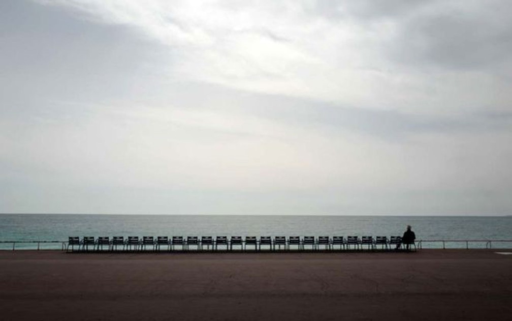 Um homem observa o Mediterrâneo na avenida Promenade des Anglais, em Nice, na França. As regras de isolamento social no país começaram a valer nesta última semana — Foto: Valery Hache/Getty Images/BBC