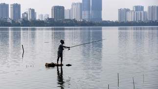 Um homem pesca no Lago West, o maior lago de água doce de Hanói, no Vietnã — Foto: Nhac NGUYEN / AFP
