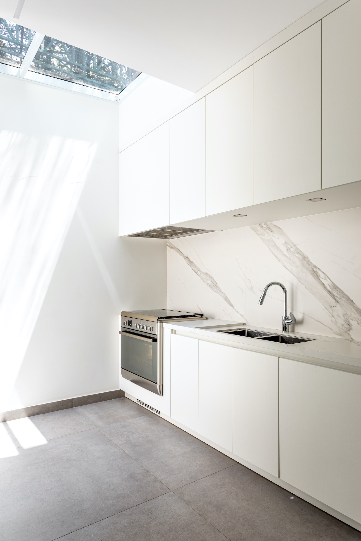 COZINHA | O branco predomina a cozinha. A claraboia foi uma solução para trazer mais iluminação natural para o ambiente (Foto: Divulgação / )