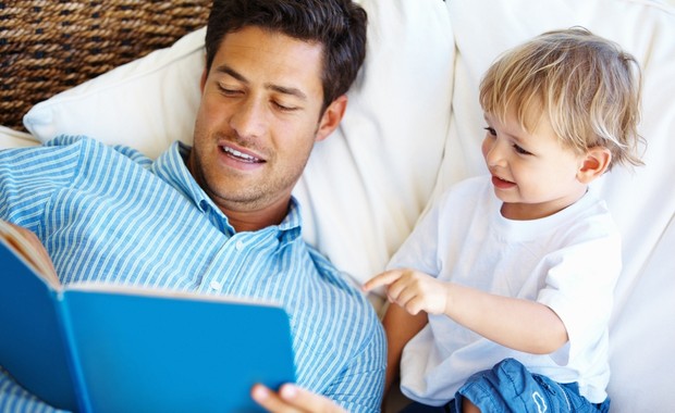 Pai e filho lendo livro juntos no sofá (Foto: Shutterstock)