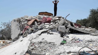 Jovem sírio é visto sobre monte de escombros a cidade rebelde de Jisr al-Shughur, na província de Idlib, no noroeste do país, alvo de um ataque aéreo russo, que matou sete pessoas, sendo quatro crianças — Foto: OMAR HAJ KADOUR / AFP
