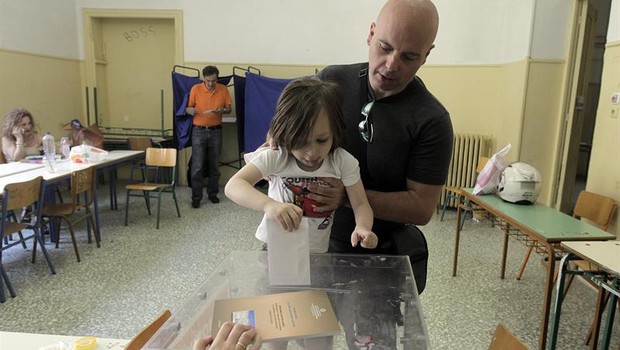 Criança ajuda pai a votar em referendo da Grécia (Foto: EFE)