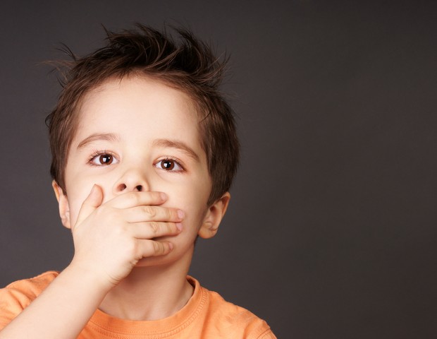 Criança preocupada ou sufocada com a mão na boca (Foto: Shutterstock)