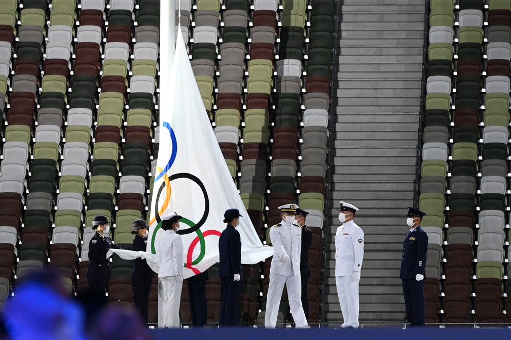 A bandeira olímpica é retirada e dobrada durante a cerimônia de encerramento dos Jogos Olímpicos de Tóquio, no Estádio Olímpico — Foto: Adek BERRY / AFP