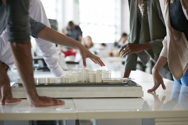 Close-up of co-workers gathered around architectural model (Foto: Getty Images)