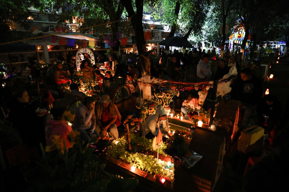 Pessoas fazem homenagens ao redor do túmulo de entes queridos no cemitério Los Reyes, na Cidade do México, durante as celebrações do Dia dos Mortos nesta sexta (1º) — Foto: Eduardo Verdugo/AP