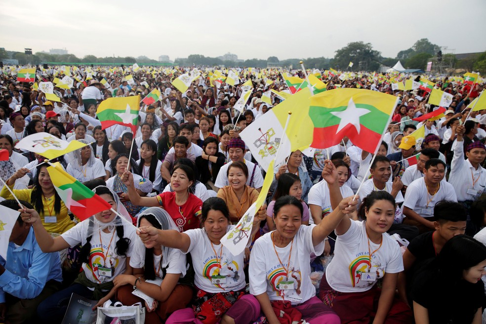 Católicos com bandeiras de Mianmar e do Vaticano se reuniram para acompanhar a missa do Papa Francisco no estádio de futebol de Yangon, nesta quarta-feira (29)  (Foto: Max Rossi/ Reuters)
