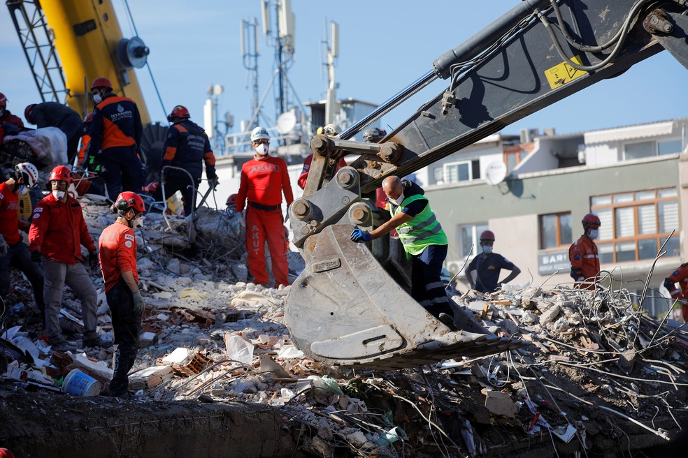 Equipes de resgate fazem buscas nos escombros de um prédio que desabou em Izmir, na Turquia — Foto: Kemal Aslan/ReutersEquipes de resgate fazem buscas nos escombros de um prédio que desabou em Izmir, na Turquia — Foto: Kemal Aslan/Reuters