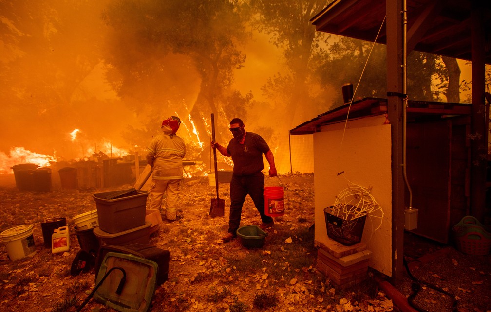 Moradores tentam salvar casa em New Long Valley, na Califórnia, no sábado (4) (Foto: Noah Berger / AFP)