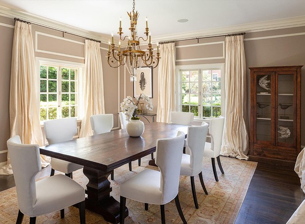 Na sala de jantar, portas francesas cercam a mesa de madeira e as cadeiras brancas (Foto: Berkshire Hathaway HomeServices/ Reprodução)