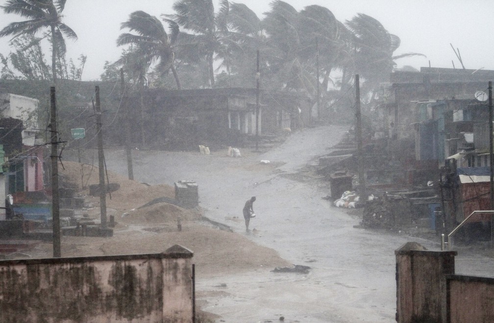 Homem enfrenta nesta quinta-feira (11)forte chuva causada pelo ciclone Titli perto da praia Arjipalli, no estado de Orissa, na Índia — Foto: AP Photo