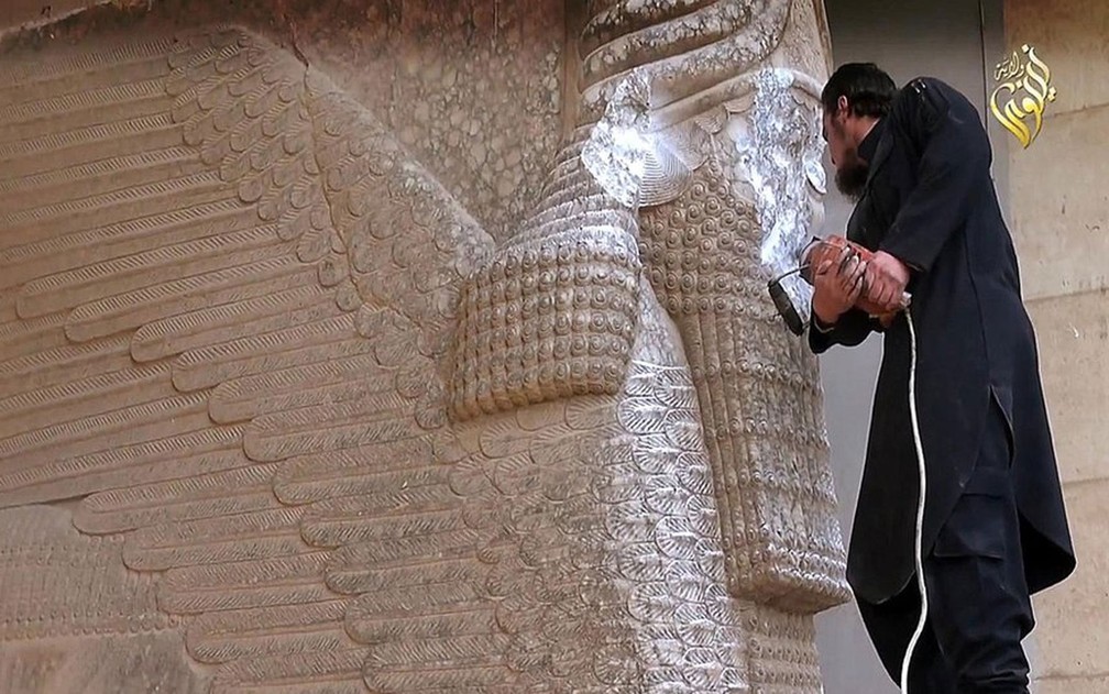 Os militantes do Estado Islâmico desfiguraram uma estátua de lamassu, criatura mítica que protege a entrada de palácios assírios — Foto: Vídeo veiculado pelo Estado Islâmico