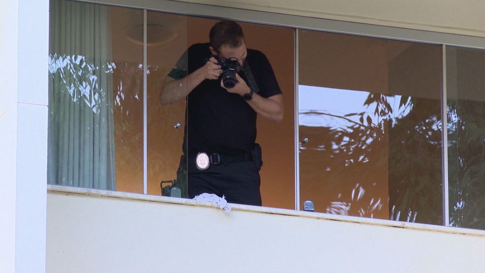 Perito da Polícia Civil registra fotos da janela de um apartamento na Asa Sul de onde uma moradora de 60 anos caiu e morreu — Foto: TV Globo/Reprodução