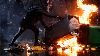 Uma pessoa move uma lata de lixo ao lado das chamas durante uma marcha para marcar o Dia Internacional da Mulher em Paris, França, 8 de março de 2023 — Foto: REUTERS/Benoit Tessier