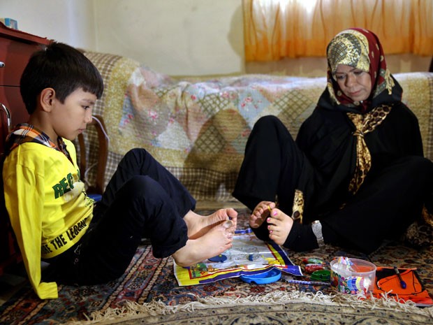 Roohollah Jafar, de 9 anos, tem aulas de pintura com a professora aposentada (Foto: Ebrahim Noroozi/AP)