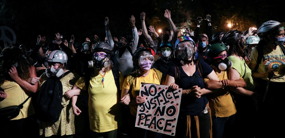 'Muro de Mães' se forma entre manifestantes e forças de segurança neste domingo (19) em Portland, nos EUA — Foto: Caitlin Ochs / Reuters