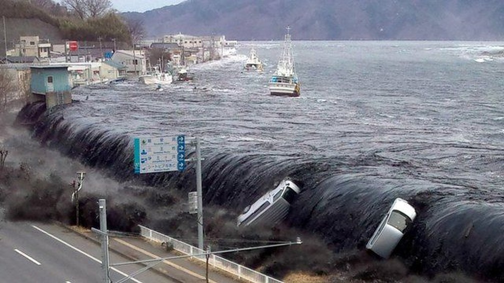 O mar superou barreiras e invadiu cidades, arrastando carros e barcos, como em Miyako — Foto: Jiji Press/AFP/Arquivo