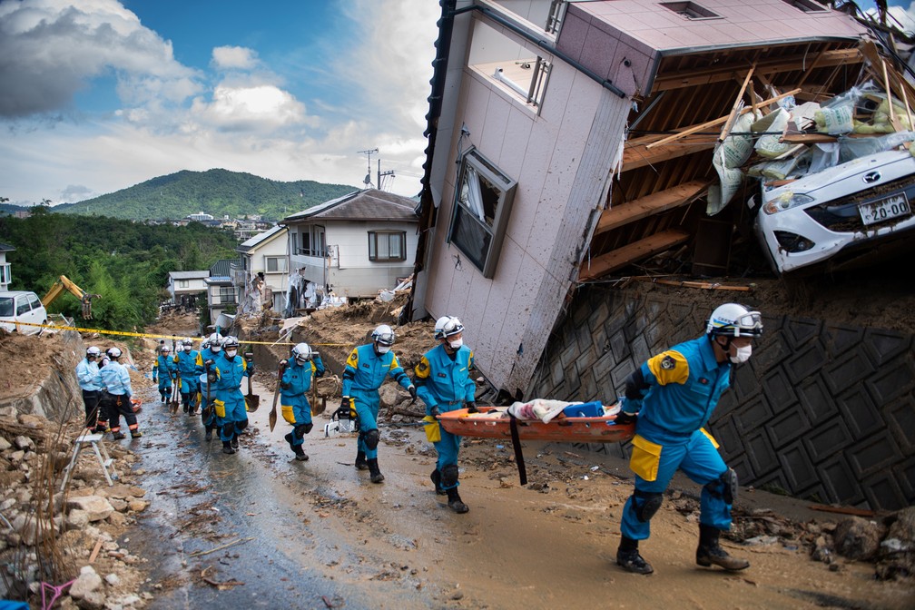 Policiais chegam para limpar os escombros de uma rua atingida pela inundação em Kumano, no Japão. Equipes de resgate trabalham para alcançar moradores presos após as chuvas devastadoras que mataram pelo menos 81 pessoas (Foto: Martin Bureau/AFP)