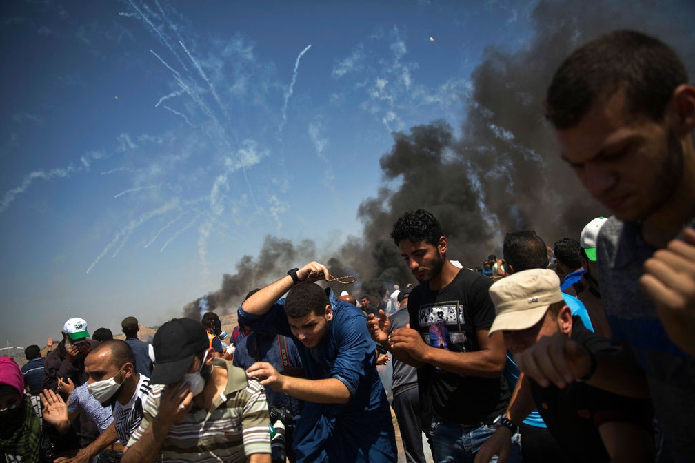 GÃ¡s lacrimogÃªneo Ã© lanÃ§ado contra manifestantes palestinos na Faixa de Gaza, nesta sexta-feira (8)  (Foto: Khalil Hamra/ AP)