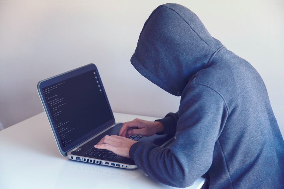 Pessoa usando computador com o rosto escondido — Foto: Pexels