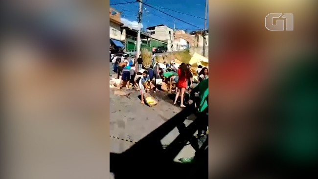 Caminhão tomba carga de frango, dono resolve doar e multidão disputa comida