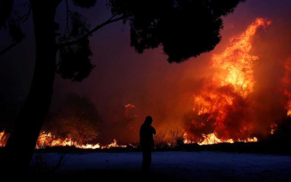 Homem observa chamas em incêndio florestal na cidade de Rafina, perto de Atenas, na Grécia, na segunda-feira (23) (Foto: Reuters/Costas Baltas)