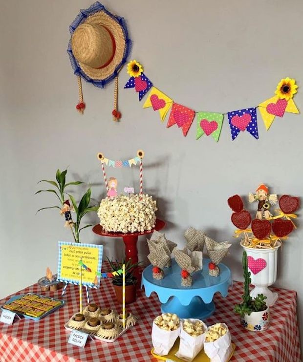 Chapéu de palha e bandeirolas na parede, bolo de pipocas e doce de beterraba no palito decoram a mesa (Foto: Montando Minha Festa / Pinterest)